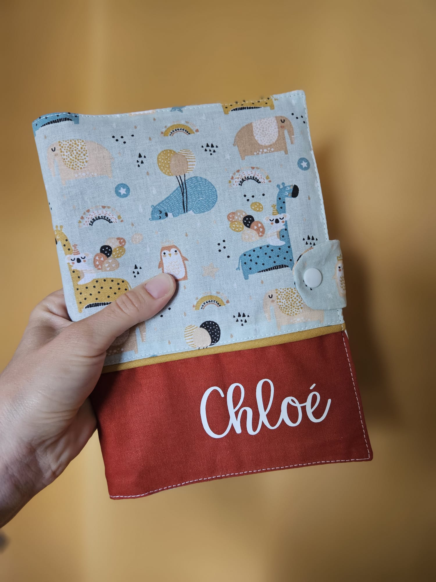 Carnet de santé personnalisé au prénom de Chloé. Tissu motifs "au dodo" et uni terracotta, passepoil ocre – modèle Tata Créa