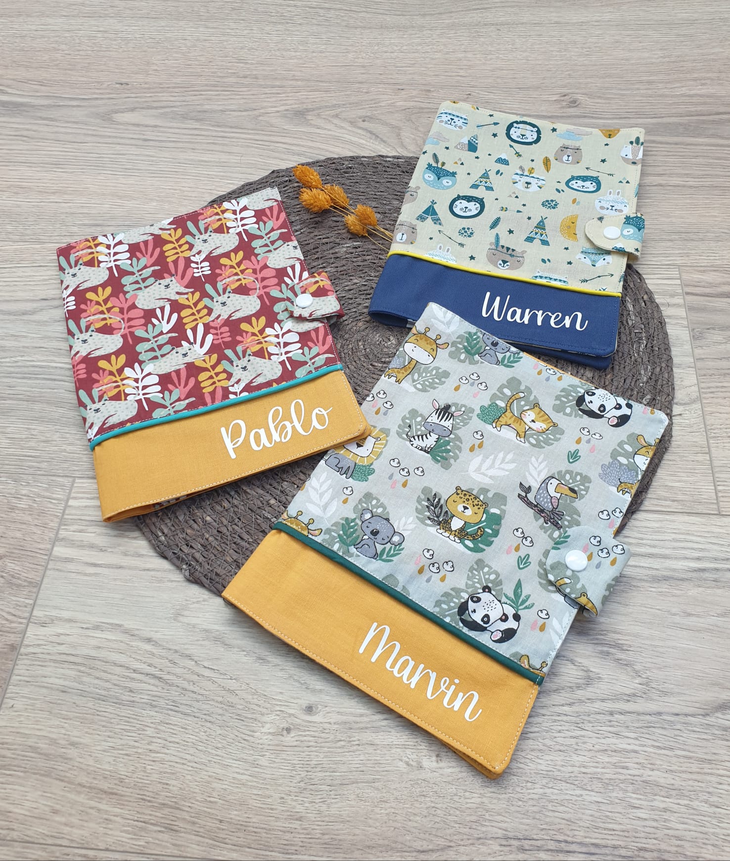 Trois protège carnet de santé personnalisés au noms de Warren, Pablo et Marvin. Couleurs et motifs des tissus choisis par les parents – modèle Tata Créa