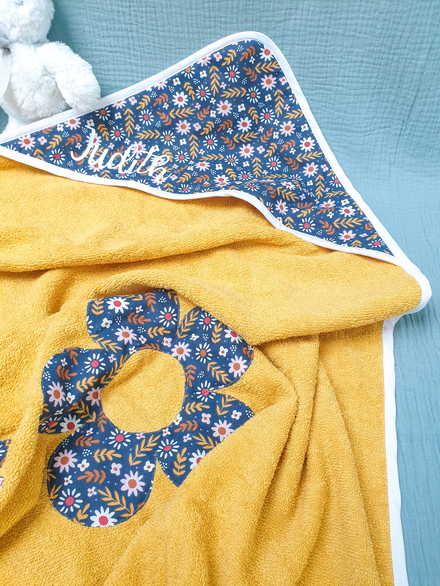 Cape de bain personnalisée au nom de Judith, en éponge moutarde, coton à motifs floraux, biais blanc – modèle Tata Créa