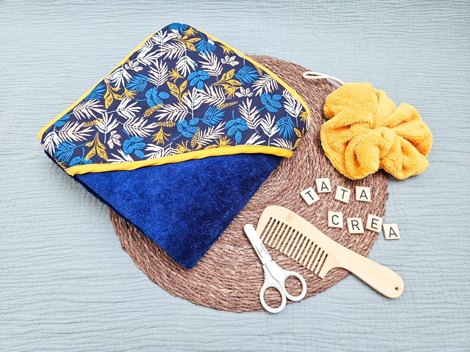 Cape de bain grand format - modèle tata créa. Coton à motifs "feuillage bleu", biais jaune, éponge bleue foncée, en attente de personnalisation.