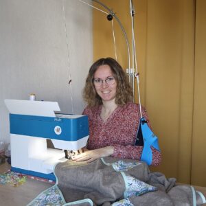 Mathilde, alias Tata créa, devant sa machine à coudre, avec son installation de poste de travail (Perdelle)