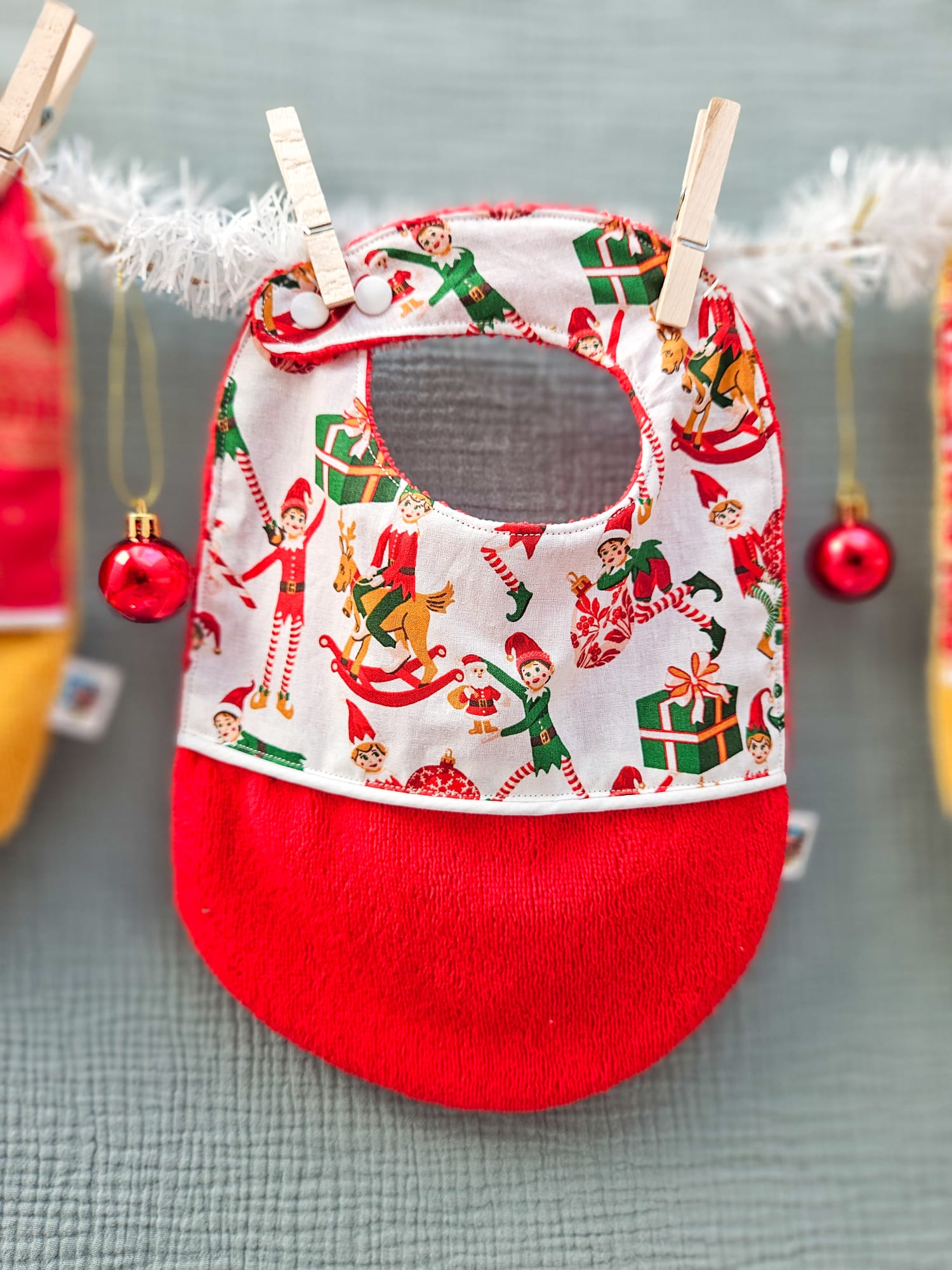 Bavoirs de Noël bébé (4 mois et plus). Coton à motifs "lutins farceurs", liseré intermédiaire blanc, éponge rouge – modèle Tata Créa